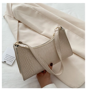 Detail of cream baguette bag featuring crocodile pattern and golden metal hardware