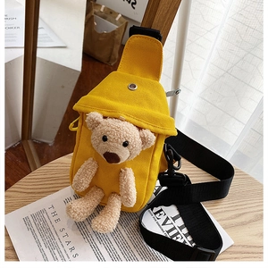 Close-up of bright yellow canvas chest bag with a 3D plush teddy bear mascot on a magazine