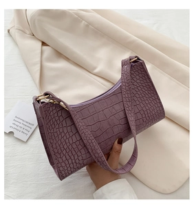 Detail of purple crocodile embossed leather underarm bag with gold zipper and strap