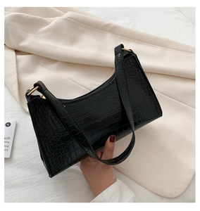 Detail of black crocodile texture faux leather with gold zipper on baguette shoulder bag