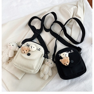 Detail of canvas crossbody bag showing 3D bear decor and adjustable shoulder strap