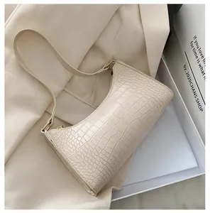 Close-up of cream white crocodile embossed shoulder bag with gold zipper detail