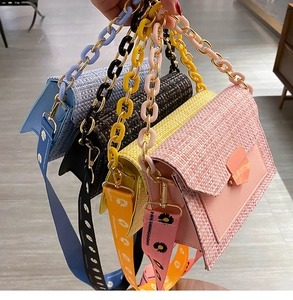 Macro shot of colorful tweed crossbody bags with floral straps and chunky chain handles