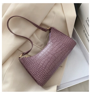 Detail shot of purple baguette bag with crocodile texture and gold metal hardware accents