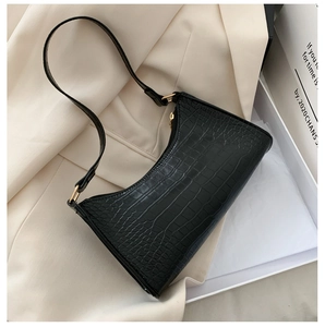 Close-up of black crocodile embossed baguette bag with sleek zip and shoulder strap