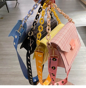Close-up of woven texture handbags with daisy wide straps and colorful chain handles