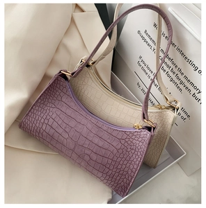 Detail shot of purple and cream faux crocodile leather baguette bags with gold zippers