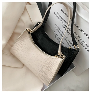 Detail of crocodile pattern baguette bags in black and cream with gold hardware
