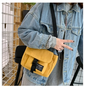 Detail of yellow canvas messenger bag with black buckle closure and adjustable strap