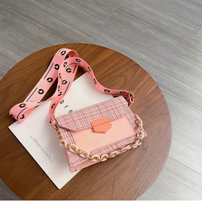 Detailed shot of pink tweed crossbody bag with daisy strap and decorative chain links
