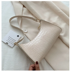 Close-up of off-white baguette bag with crocodile pattern and golden zipper detail