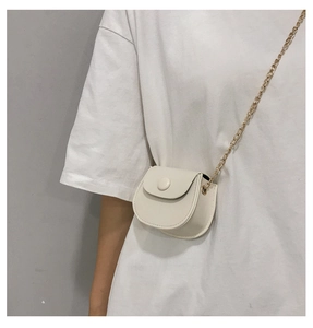 Minimalistische roomwitte mini zadeltas met gouden ketting over de schouder van model