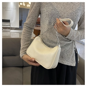 Detail of a creamy white underarm bag with silver chain and textured synthetic leather