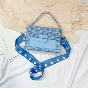 Close-up of blue tweed crossbody bag with daisy chain strap and acrylic handle
