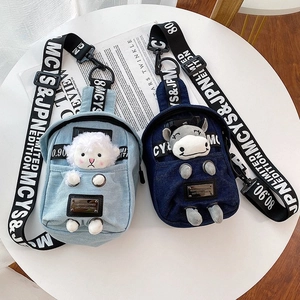 Detail of denim crossbody bags featuring plush animal charms and branded woven straps