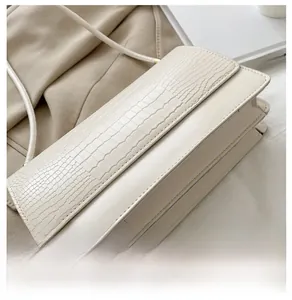 Detail view of cream white faux crocodile leather crossbody bag with accordion folds
