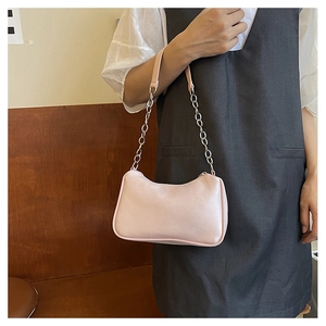 Close-up of pink PU leather underarm bag with silver chain strap on model