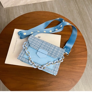 Detail of light blue tweed crossbody bag with daisy strap and acrylic chain link