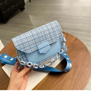 Close-up of light blue tweed crossbody bag featuring daisy print wide strap and chain