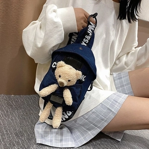 Detail of dark blue denim chest bag featuring 3D plush bear and branded wide strap
