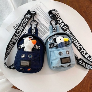 Detail of denim crossbody bag featuring cute plush duck charm and stylish lettered strap