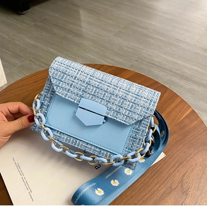 Detail of light blue woven crossbody bag with tweed texture and floral print strap