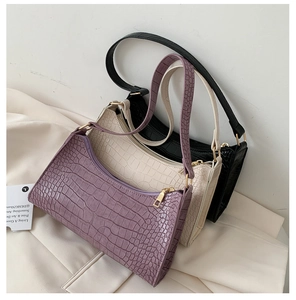 Detail of crocodile pattern texture on purple, white, and black baguette bags