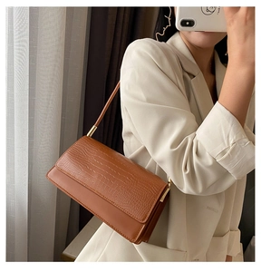 Detail of brown faux crocodile leather shoulder bag with elegant gold metal hardware