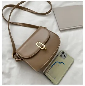 Detailansicht der braunen Satteltasche aus Leder mit goldener Schnalle auf Stoff
