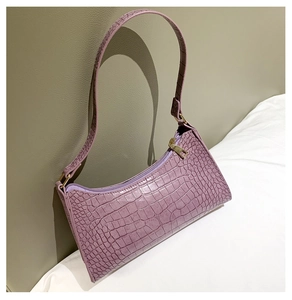Detail of purple faux crocodile texture on a baguette bag with gold zipper accents