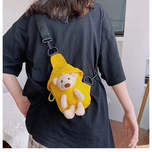 Detail of yellow canvas cross-body bag with 3D teddy bear worn by model