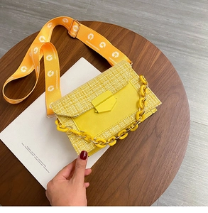 Detail of yellow tweed crossbody bag with chunky chain and daisy print wide strap
