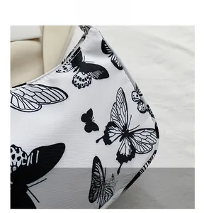 Detailed close-up of white canvas bag featuring a minimalist black butterfly printed pattern