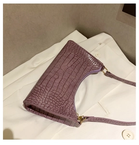 Detail of purple baguette bag with crocodile pattern texture and gold zipper accents