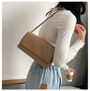 Detail view of light brown crocodile pattern baguette bag worn on shoulder