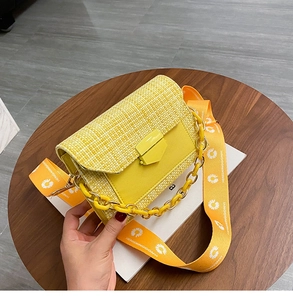 Detail of yellow woven crossbody bag with chunky chain handle and daisy floral wide strap