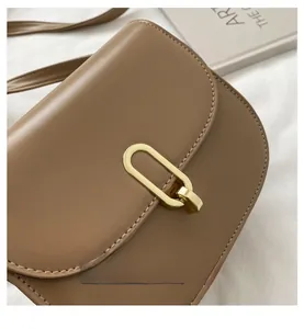 Nahaufnahme einer khakifarbenen Satteltasche aus Leder mit goldener ovaler Metallschnalle