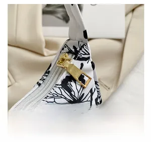 Detailed close-up of golden metal zipper puller and butterfly print on handbag