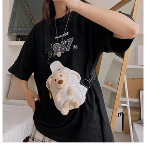 Detail of white canvas crossbody bag with cute plush brown bear decoration and strap
