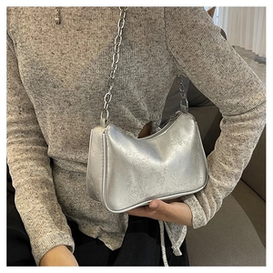 Detailed view of silver embossed underarm bag with thick metallic chain strap