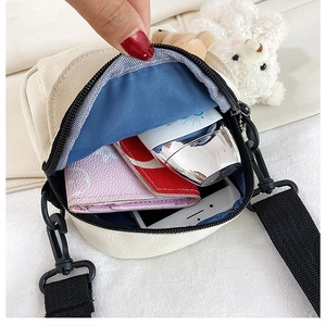 Detail view of the spacious inner compartment of the cream canvas crossbody bag