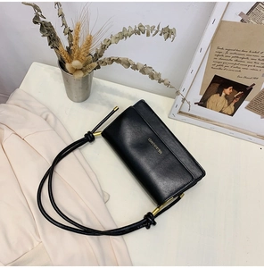 Detail of black leather crossbody bag with knot design and gold metal tube connector