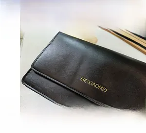 Detail view of the black textured leather material and gold brand logo on the bag