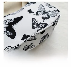Close-up of contrast color handbag showing black and white butterfly print and fine stitching