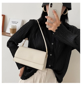Detail of cream crocodile embossed faux leather underarm bag with minimalist metal hardware