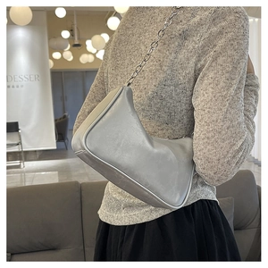 Detail of light gray underarm bag with thick silver chain strap worn by a model