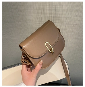 Detail einer braunen Satteltasche aus Leder mit poliertem goldenem U-Metall-Drehverschluss