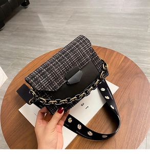 Detail of tweed flap shoulder bag with daisy print wide strap on a wooden table