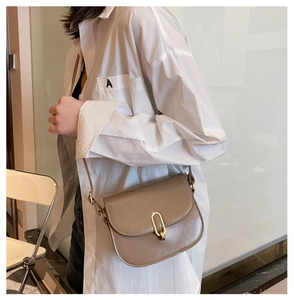 Schicke Khaki-Satteltasche aus Leder mit Goldschnalle, getragen von einem Model