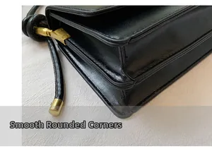 Detailed close-up of smooth rounded corners and gold buckle on a black leather handbag